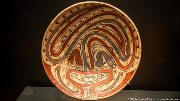 Painted ceramic plate with red curving motifs at Louvre Abu Dhabi.