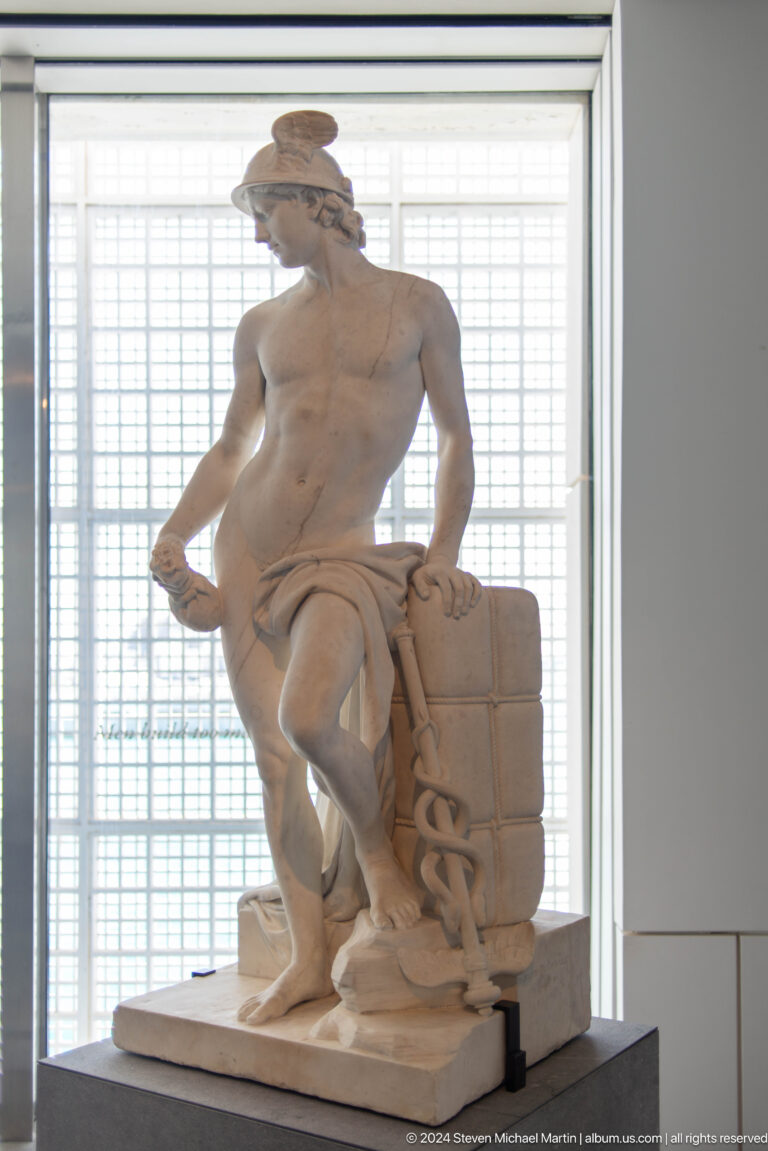 Marble male nude with drapery and block support at Louvre Abu Dhabi.