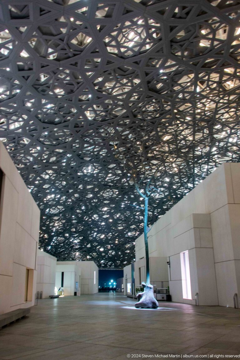 White gallery blocks beneath geometric dome at Louvre Abu Dhabi.