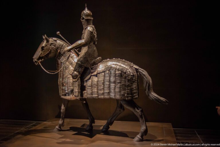 Dark equestrian sculpture against black background at Louvre Abu Dhabi.