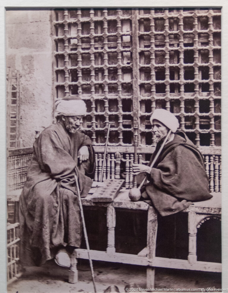 Black-and-white photograph of two robed men seated together at Louvre Abu Dhabi.
