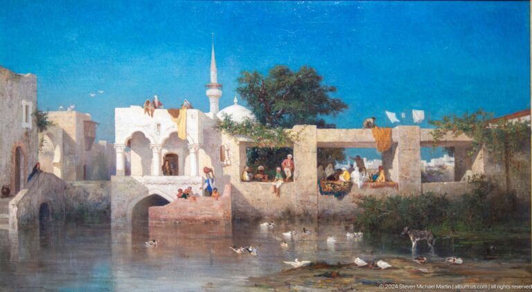 Bright village scene beside water at Louvre Abu Dhabi.
