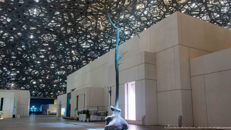 Museum gallery corner beneath layered dome at Louvre Abu Dhabi.