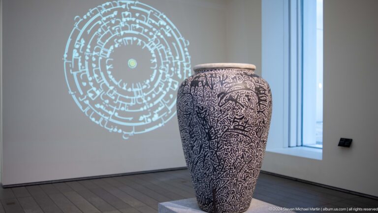 Large patterned ceramic vessel beside projected circular graphic at Louvre Abu Dhabi.