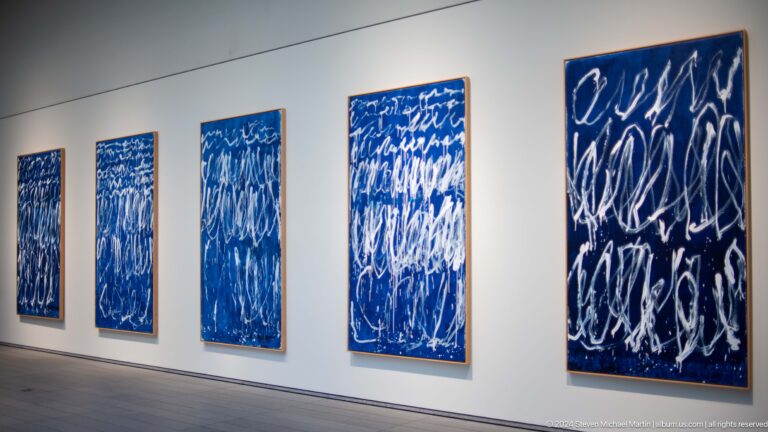 Gallery wall with vertical blue abstract paintings at Louvre Abu Dhabi.