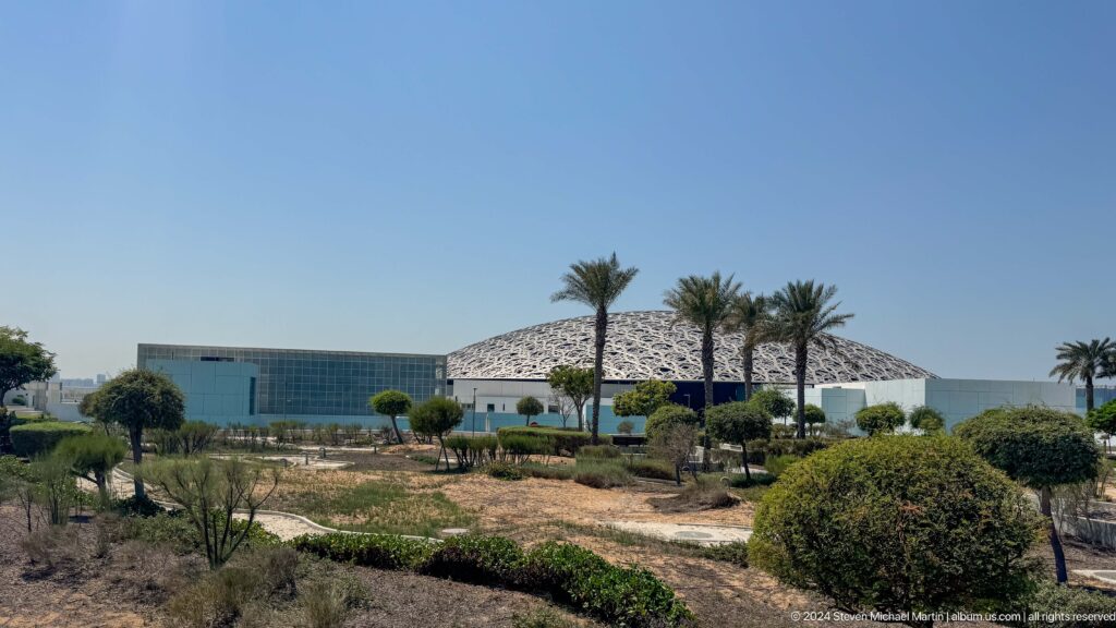 Landscaped museum grounds with palms at Louvre Abu Dhabi.
