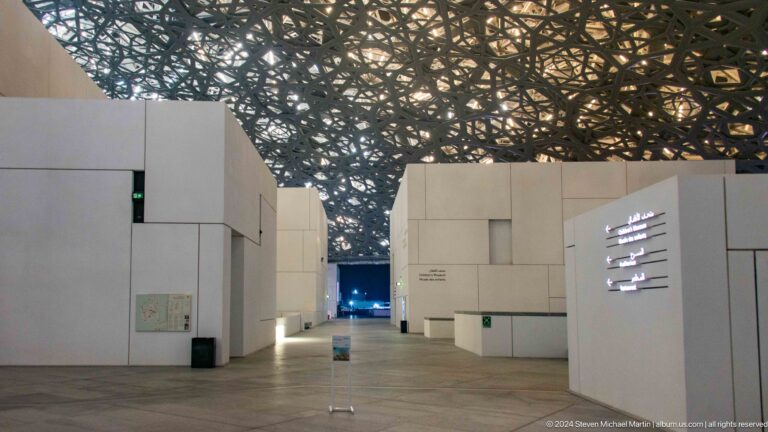 White museum blocks and signage under dome at Louvre Abu Dhabi.
