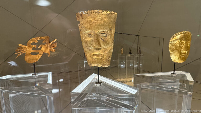 Group of ancient gold masks in display case at Louvre Abu Dhabi.