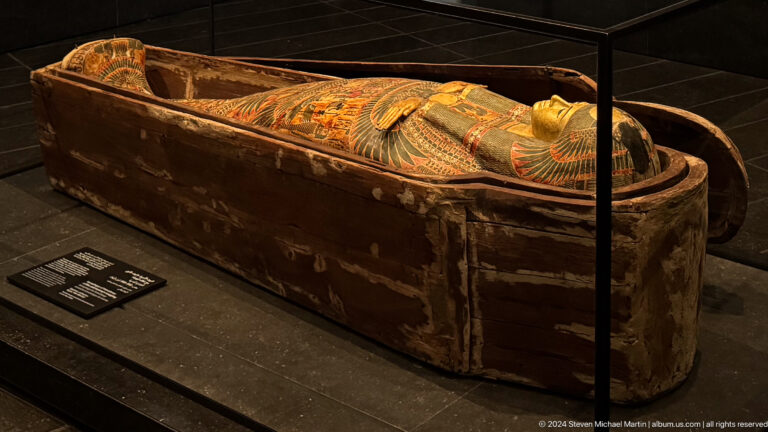 Painted sarcophagus or coffin in dark case at Louvre Abu Dhabi.