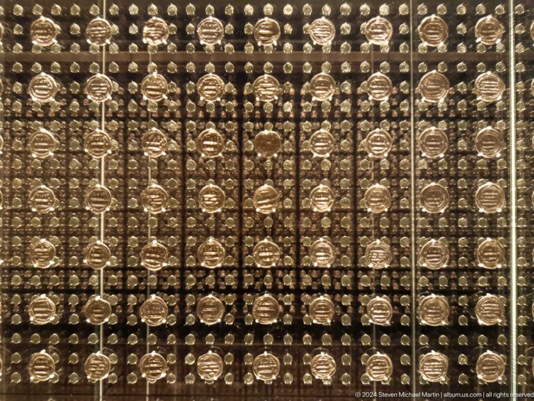 Grid display of many small sculpted heads at Louvre Abu Dhabi.
