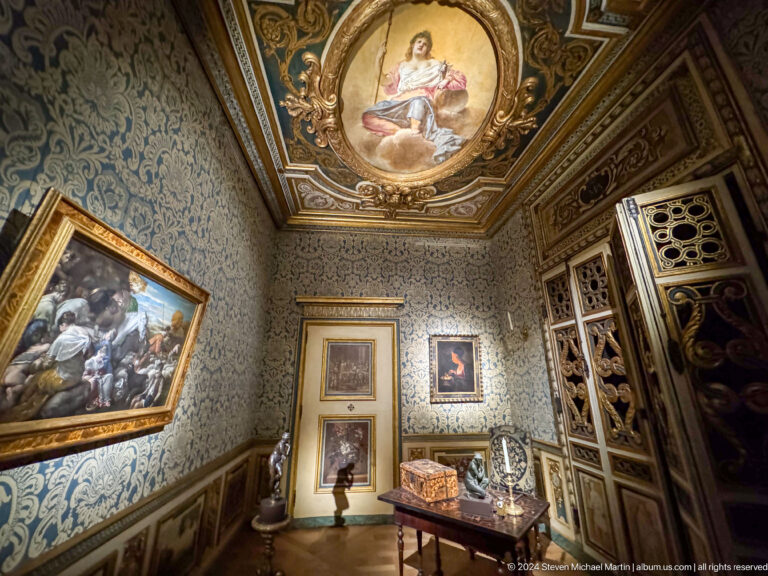 Ornate period room with painted ceiling and framed works at Louvre Abu Dhabi.