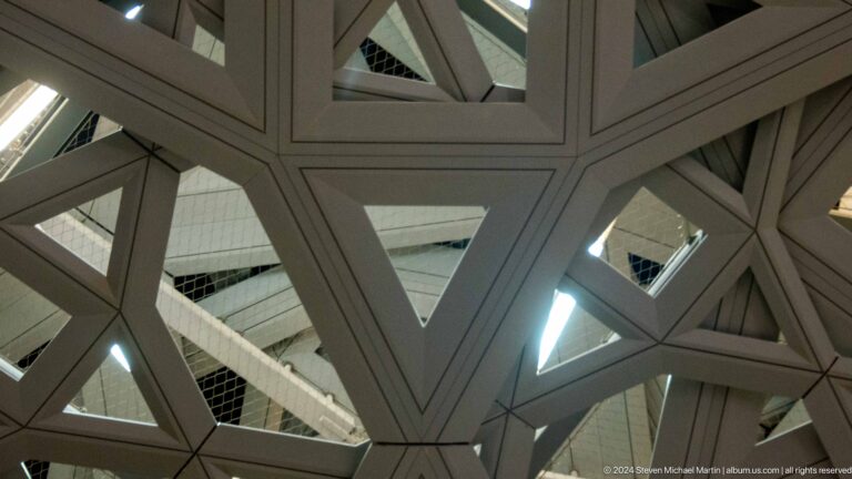 Upward view through triangular dome structure at Louvre Abu Dhabi.