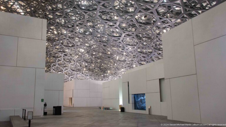 Wide central passage under perforated dome at Louvre Abu Dhabi.