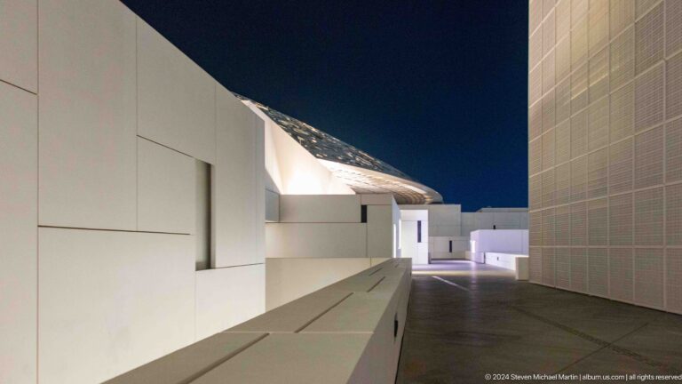 White passage between museum buildings at night at Louvre Abu Dhabi.