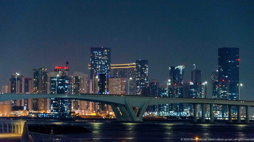 Abu dhabi skyline across water at night at Louvre Abu Dhabi.