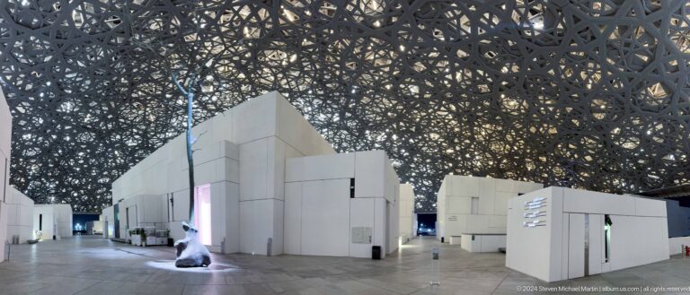 Interior gallery street beneath geometric dome at Louvre Abu Dhabi.