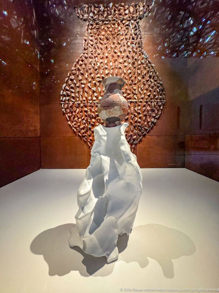 White draped sculpture before circular patterned screen at Louvre Abu Dhabi.