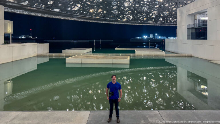 Visitor standing before reflecting pool at Louvre Abu Dhabi.
