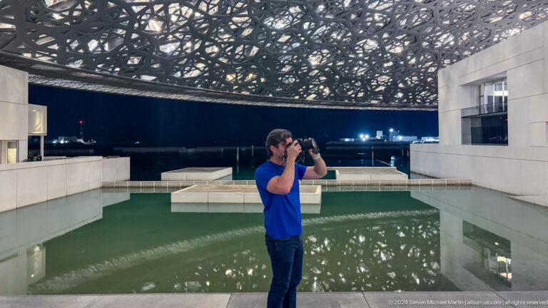 Visitor photographing the museum interior at Louvre Abu Dhabi.