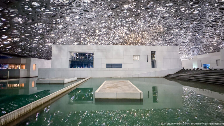 White gallery and pool under dome at Louvre Abu Dhabi.