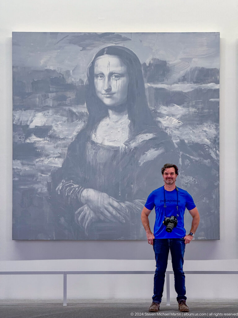 Visitor posing before enlarged mona lisa image at Louvre Abu Dhabi.