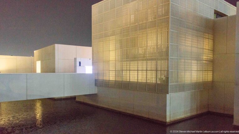 Golden translucent pavilion beside white wall at Louvre Abu Dhabi.