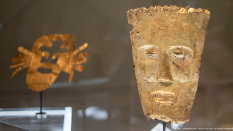 Golden ancient face mask in display case at Louvre Abu Dhabi.