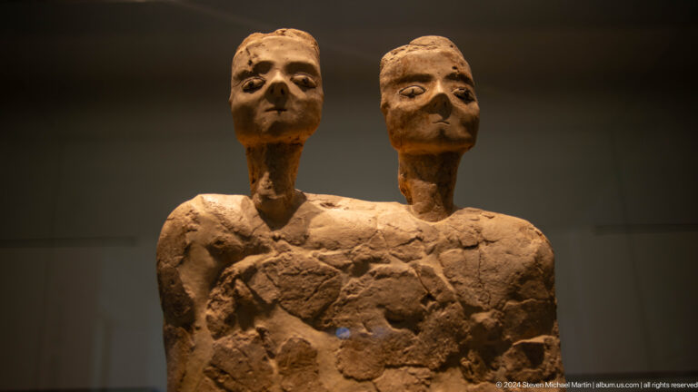 Paired ancient clay figures joined at the torso at Louvre Abu Dhabi.