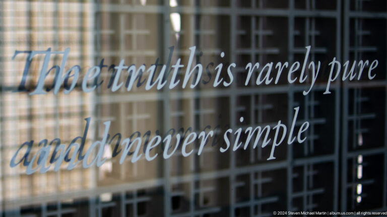 Museum quote lettering on glass wall at Louvre Abu Dhabi.