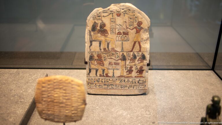 Painted funerary stela with seated figure scene at Louvre Abu Dhabi.
