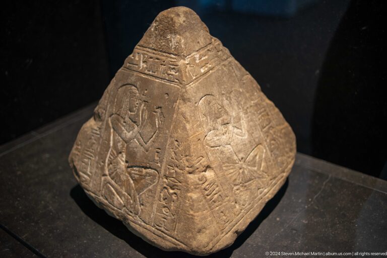 Triangular carved stone with low-relief figures at Louvre Abu Dhabi.