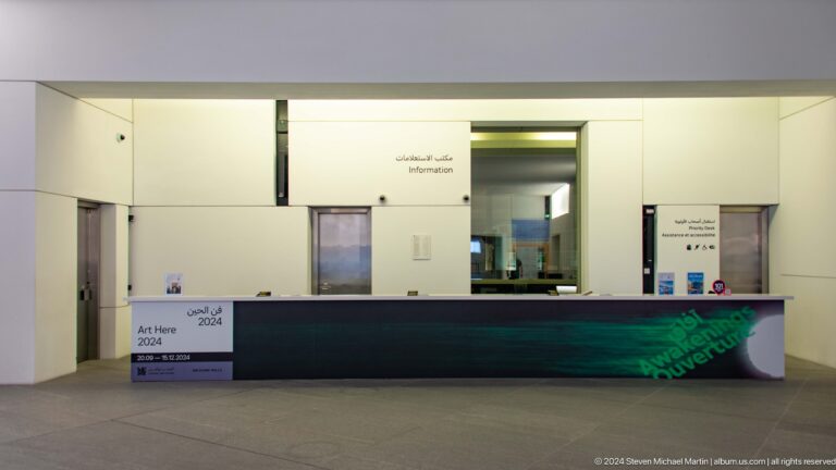 Museum reception counter in white lobby at Louvre Abu Dhabi.
