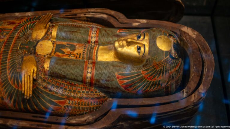 Painted egyptian coffin lid with face and crossed arms at Louvre Abu Dhabi.