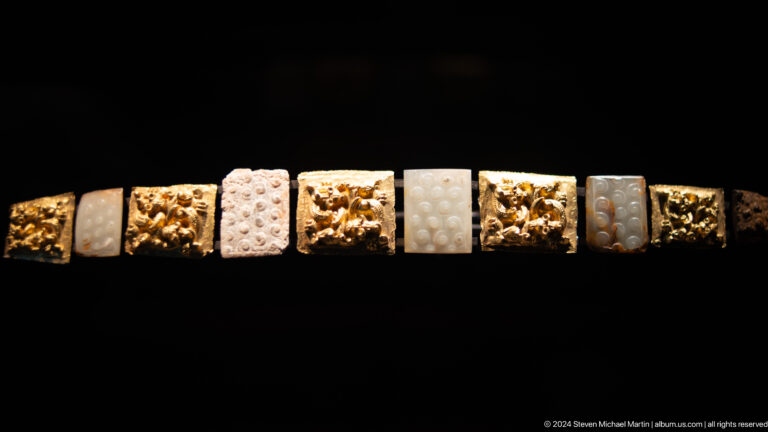 Row of small carved and patterned beads at Louvre Abu Dhabi.