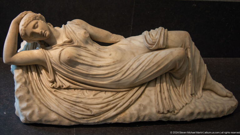 Reclining marble figure draped in cloth at Louvre Abu Dhabi.