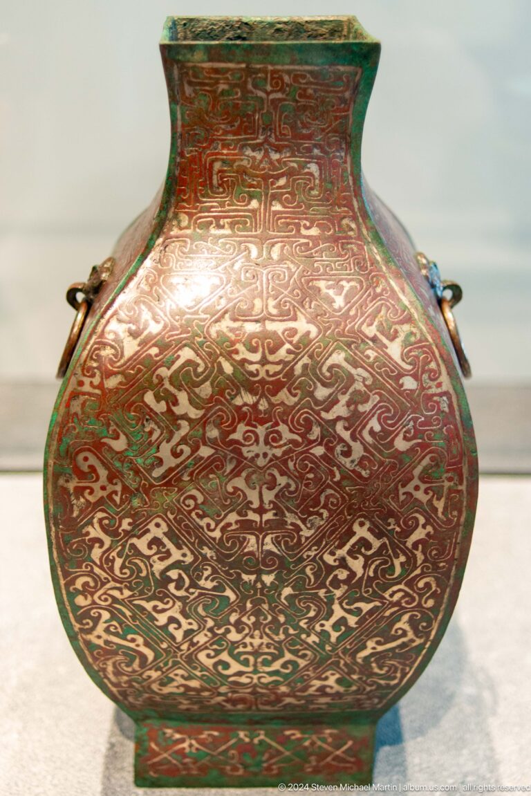 Round red and green vessel with intricate pattern at Louvre Abu Dhabi.