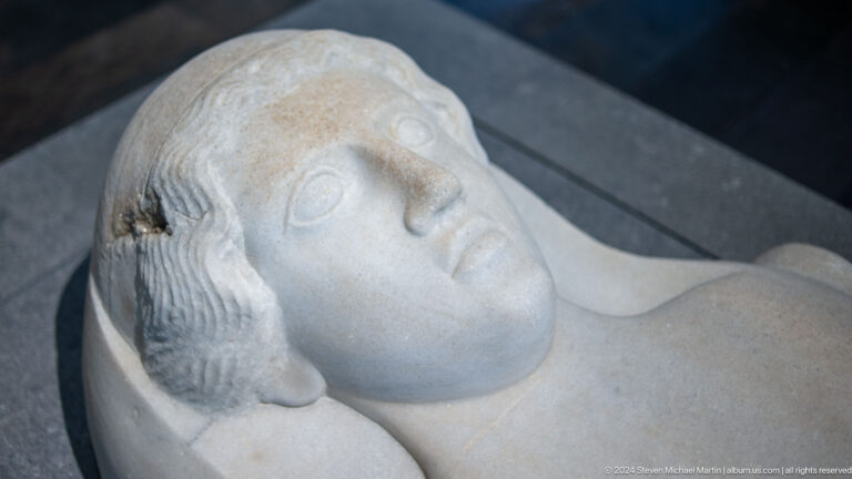 Marble head of bearded man lying on support at Louvre Abu Dhabi.