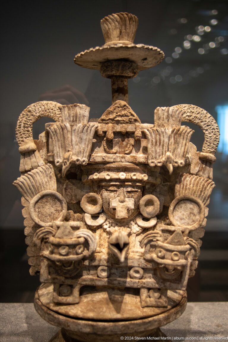 Ornate carved architectural capital with mask and scrolls at Louvre Abu Dhabi.