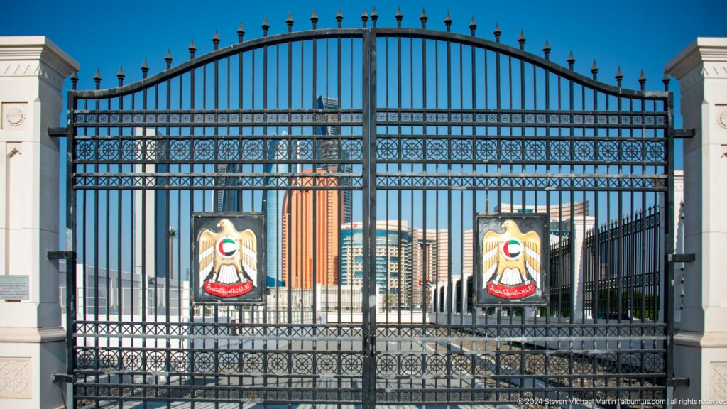 Black palace gate with repeated uae emblems.