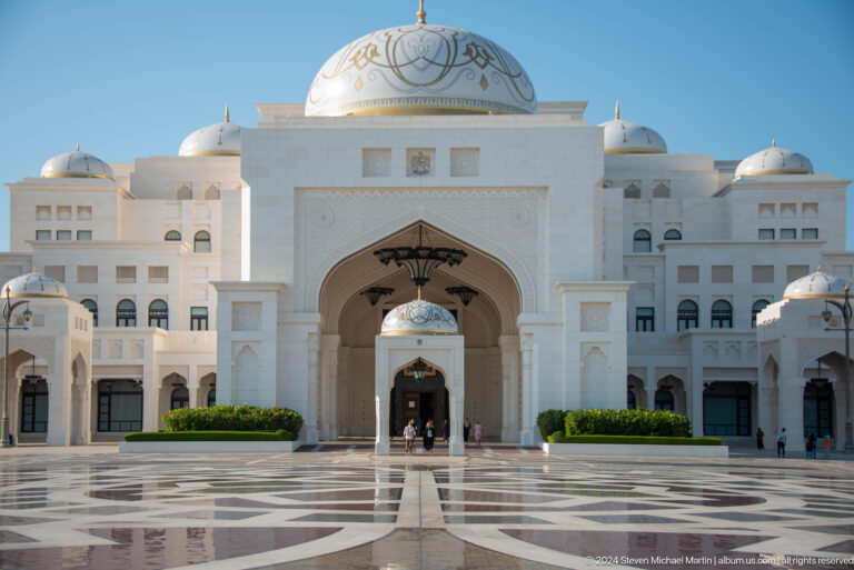 Front view of white palace façade and central arch.