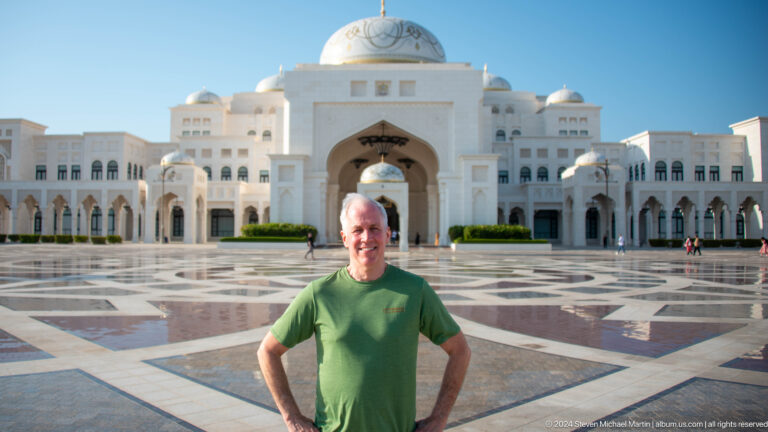 Visitor in green shirt standing before palace.