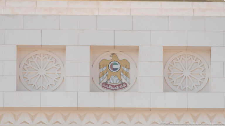 Uae emblem mounted between carved rosettes.
