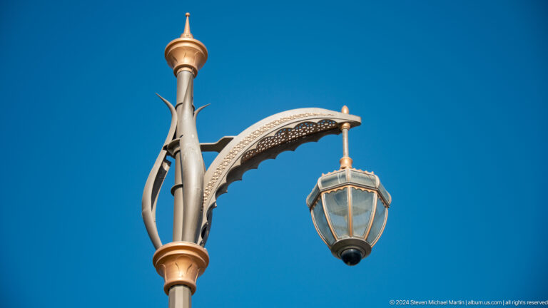 Ornate gold street lamp against blue sky.