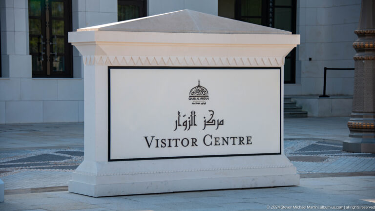 White visitor centre sign in arabic and english.