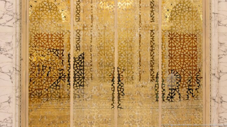 Gold calligraphy panels on translucent screen.