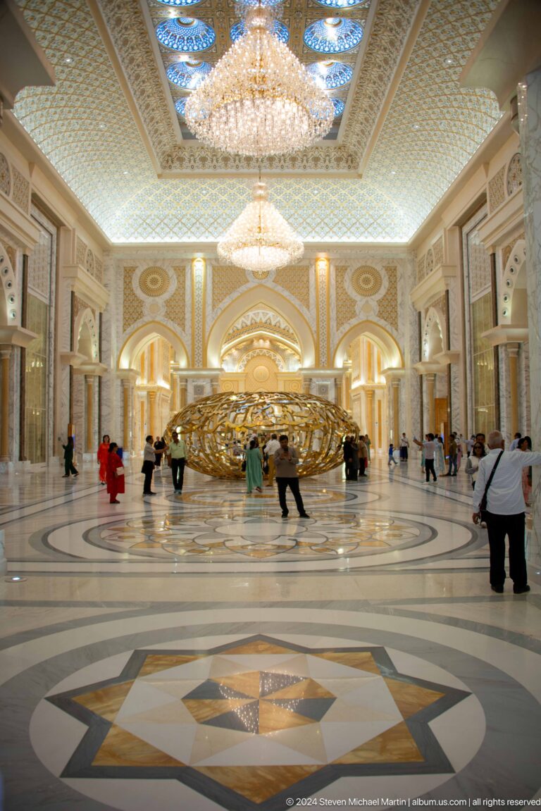 Visitors around large gold calligraphic sculpture.