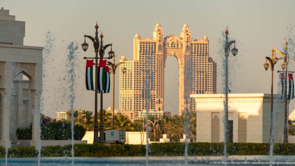 Abu dhabi skyline beyond palace grounds and flag.