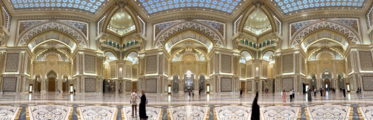 Great hall with visitors and gilded arches.