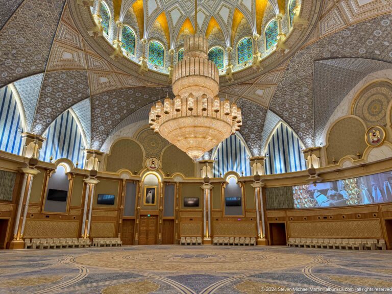 Ornate ceremonial hall with chandelier and tiered seating.