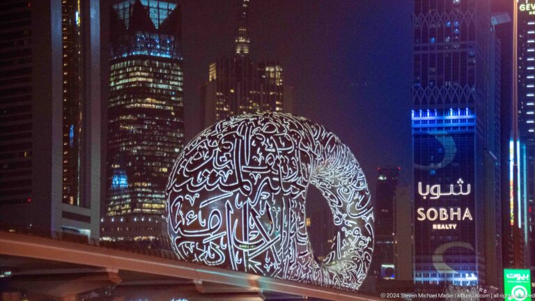 Museum of the Future illuminated at night beside Dubai’s skyline.